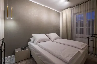 a bedroom with a bed with white sheets and a window at Na Skałce Apartment in Kraków