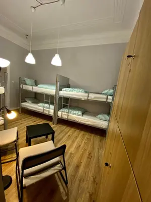 a room with three bunk beds and a table and chairs at SKY HOSTEL in Kraków