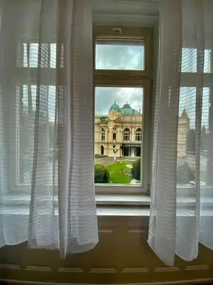 a window with white curtains in front of a building at SKY HOSTEL in Kraków