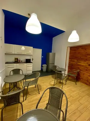 a room with tables and chairs and a blue wall at SKY HOSTEL in Kraków