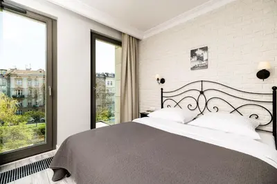 a bedroom with a large bed and large windows at Native Apartments Sukiennicza 8 in Kraków