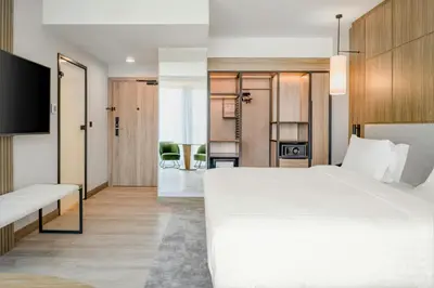 a bedroom with a large white bed and a living room at AC Hotel by Marriott Krakow in Kraków