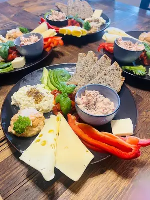 a table with plates of cheese and vegetables on it at Malinowa Chatka in Jankowice