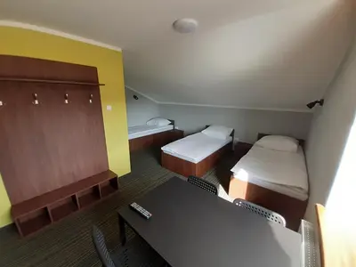 a room with two beds and a desk and a table at Willa Czajki in Oświęcim