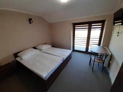 a bedroom with a bed and a table and a window at Willa Czajki in Oświęcim