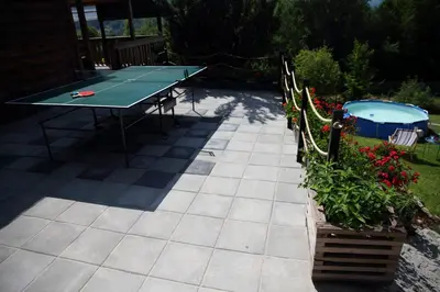 a patio with a ping pong table and flowers at Rudera u Sióstr DREWNIANY DOMEK Stróża in Stróża