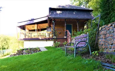 a log cabin with a porch and a bench in the grass at Rudera u Sióstr DREWNIANY DOMEK Stróża in Stróża