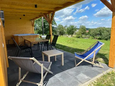 a patio with chairs and a table and a table and chairs at Domek Delux -komfortowe apartamenty, domki w Ojcowskim Parku Narodowym Z Jaccuzi in Wola Kalinowska