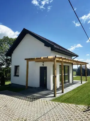 a small white house with a wooden roof at Domek Delux -komfortowe apartamenty, domki w Ojcowskim Parku Narodowym Z Jaccuzi in Wola Kalinowska