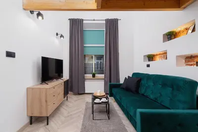 a living room with a green couch and a television at Apartment Joselewicza Cracow Kazimierz by Noclegi Renters in Kraków