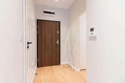 a corridor with a wooden door in a white room at Apartments nearto Main Railway Station in Kraków