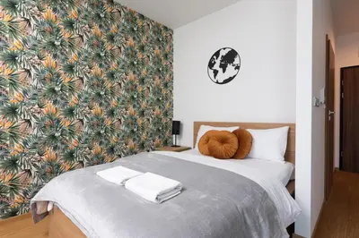 a bedroom with a large bed with a tropical wallpaper at Apartments nearto Main Railway Station in Kraków