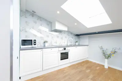 a kitchen with white cabinets and a skylight at Krupnicza Modern Old Town Apartments - by Upstairs in Kraków