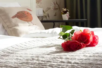 a bouquet of red roses sitting on a bed at Krupnicza Modern Old Town Apartments - by Upstairs in Kraków