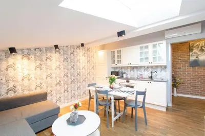 a kitchen and a living room with a table and chairs at Krupnicza Modern Old Town Apartments - by Upstairs in Kraków