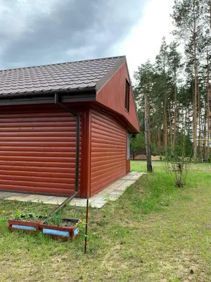 a red shed with a black roof in a field at Ranczo Wilka z kominkiem in Chrzanów