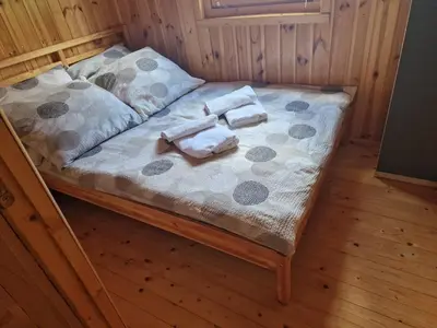 a bed in a wooden room with towels on it at Domki pod Brzozą in Czarnocin