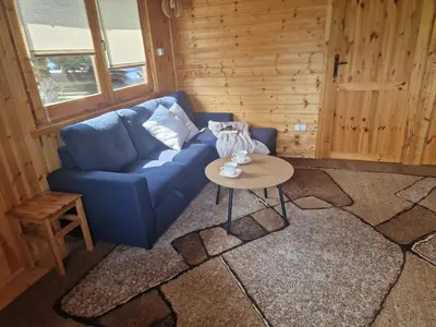 a living room with a blue couch and a table at Domki pod Brzozą in Czarnocin