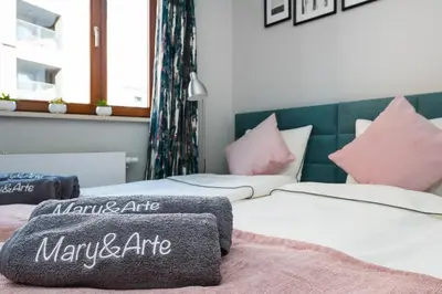 two beds in a room with pink and white pillows at Mary&Arte Apartments Browar Lubicz in Kraków