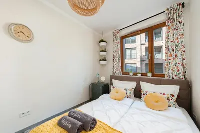 a bedroom with a bed with a clock on the wall at Mary&Arte Apartments Browar Lubicz in Kraków