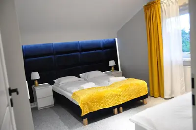 a bedroom with a large bed with a blue headboard at Apartament Willa Pod Sosnami Zator Przeciszów in Zator