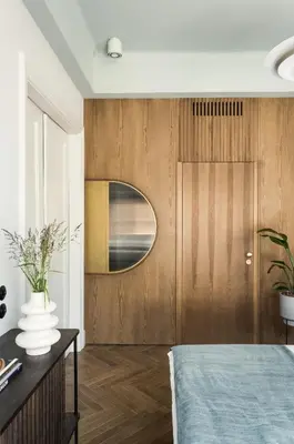 a bedroom with a wooden door with a round mirror at Angelus Apartments in Kraków