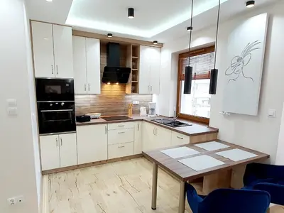 a kitchen with white cabinets and a wooden table at PARK GRZEGÓRZKI in Kraków