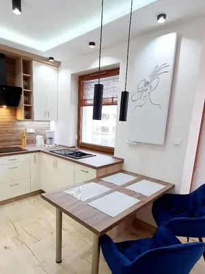 a kitchen with a wooden table and blue chairs at PARK GRZEGÓRZKI in Kraków