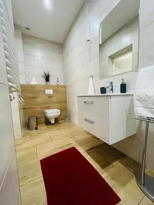 a bathroom with a toilet and a red rug at Gladiator Noclegi Zator II in Zator
