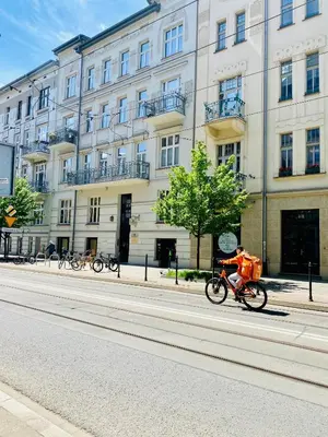 a person riding a bike down a street in front of a building at Beautiful studio for couples with Air Conditioning - Old Town & Main station in Kraków