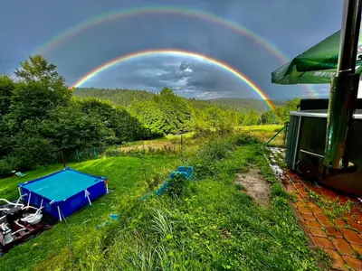 a rainbow in the sky over a field with a table at Ranczo Targoszów in Targoszów