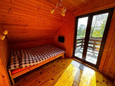 a room with a bed in a cabin with a window at Ranczo Targoszów in Targoszów