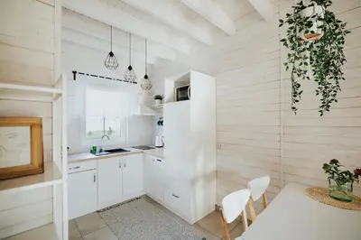a kitchen with white cabinets and a table and chairs at Domki Beskidowelove Gierałtowiczki A in Zator