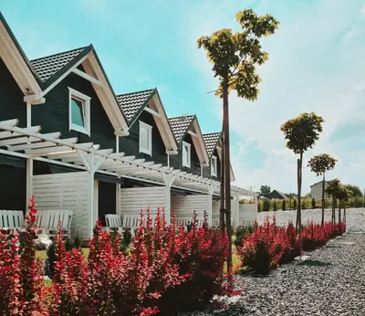 a row of houses with red flowers in front of them at Domki Beskidowelove Gierałtowiczki A in Zator
