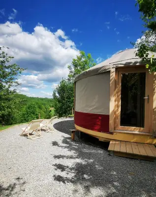 a caravan with a tent and two chairs on a gravel road at LushHills - Stylowa i Naturalna Jurta in Regulice