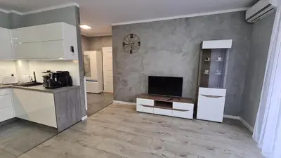 a kitchen with white cabinets and a tv on a wall at Apartament DeLuxe 3 in Oświęcim
