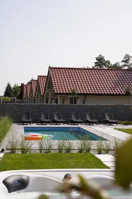 a swimming pool with chairs and a building at Apartamenty na Dworskiej - BLISKO ENERGYLANDIA ZATORLAND in Spytkowice