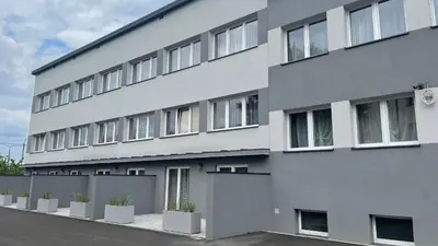 a white building with potted plants in front of it at Aparthotel WADOWICE & Hostel GENERY in Wadowice