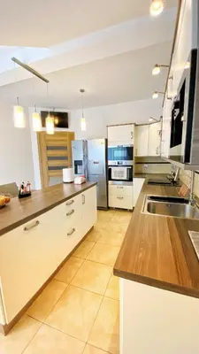 a large kitchen with white cabinets and wooden counter tops at Apartament Premium Skawina in Skawina