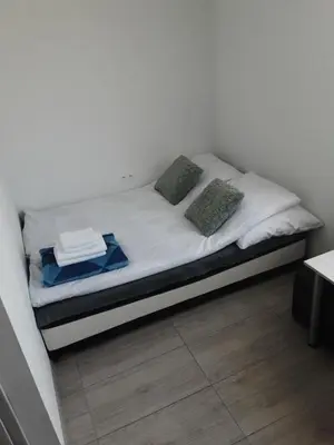 a bed with white sheets and green pillows on it at Ojcowski Las in Biały Kościół