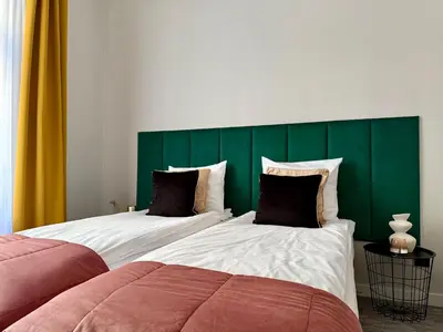 two beds in a bedroom with a green headboard at Milla Apartments in Kraków