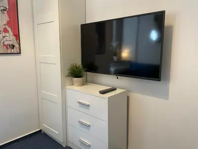 a flat screen tv on a wall with a dresser at Milla Apartments in Kraków