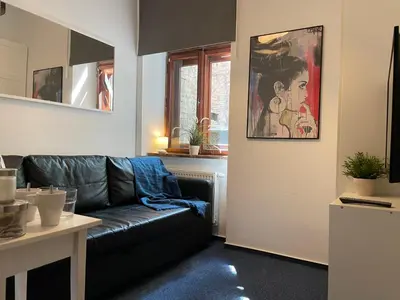 a living room with a black leather couch and a table at Milla Apartments in Kraków