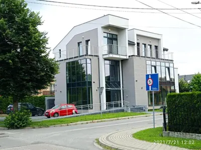 a white building with a red car in front of it at Apartamenty Kasztanowa Zator in Zator