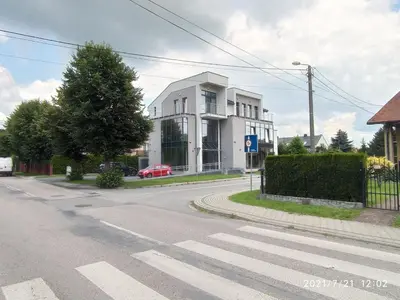 an empty street with a white building on the corner at Apartamenty Kasztanowa Zator in Zator