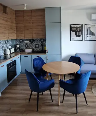 a kitchen with a table and blue chairs in a room at Apartamenty Parkowe D9 z garażem in Oświęcim
