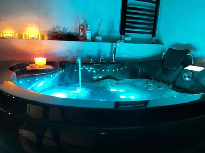 a bathroom with a blue tub with a candle in it at Jacuzzi Rakowicka Top Apartments in Kraków