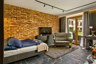 a bedroom with a brick wall and a bed and a chair at Jacuzzi Rakowicka Top Apartments in Kraków