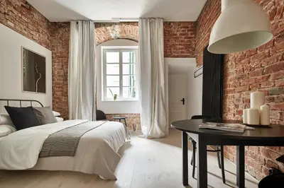 a bedroom with a brick wall and a bed and a table at OLD NEW - Prime Location on Main Square in Kraków