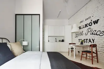 a bedroom with a bed and a table and a kitchen at OLD NEW - Prime Location on Main Square in Kraków